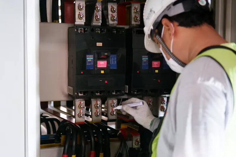 Technician inspecting an electrical distribution panel